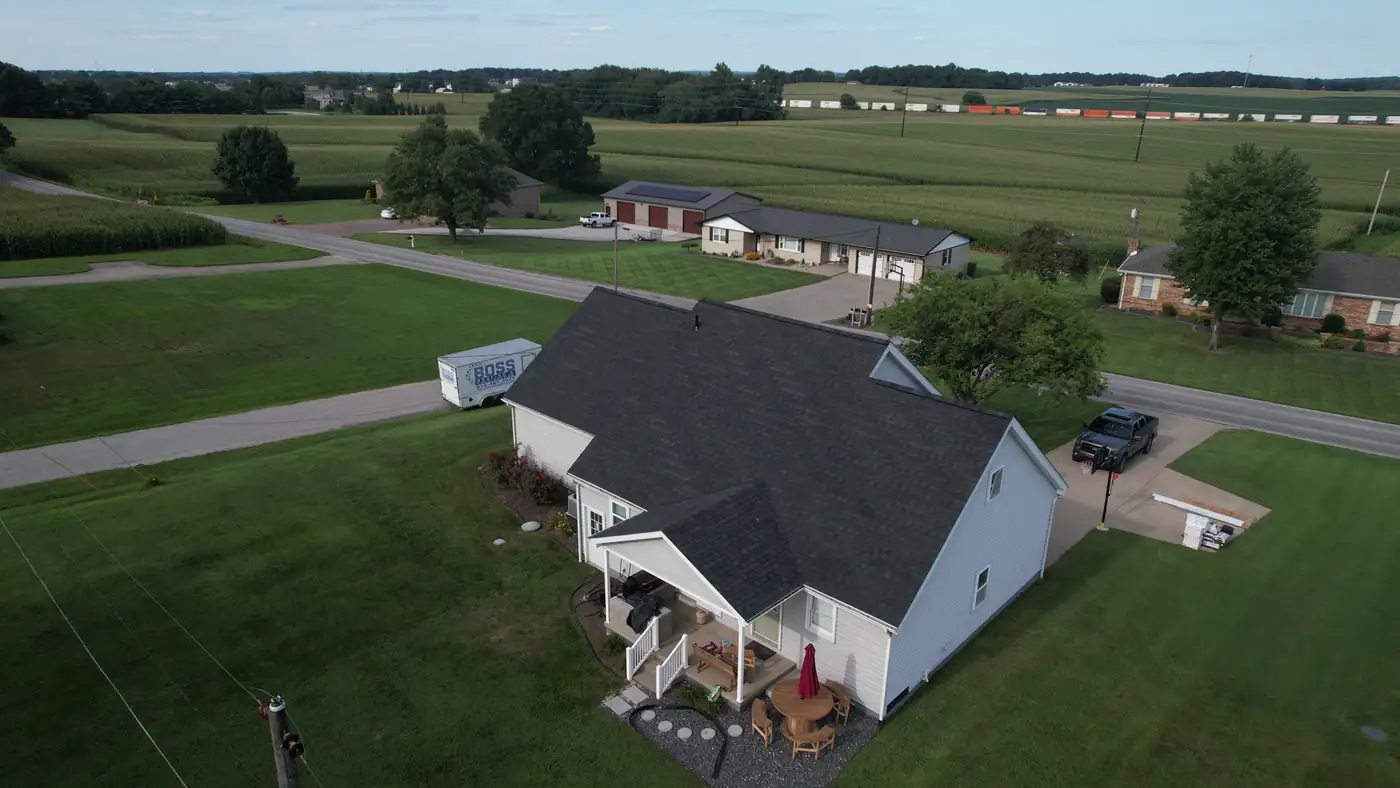 Aerial view of a home with a dark shingle roof in a Southern Indiana subdivision, farm fields behind