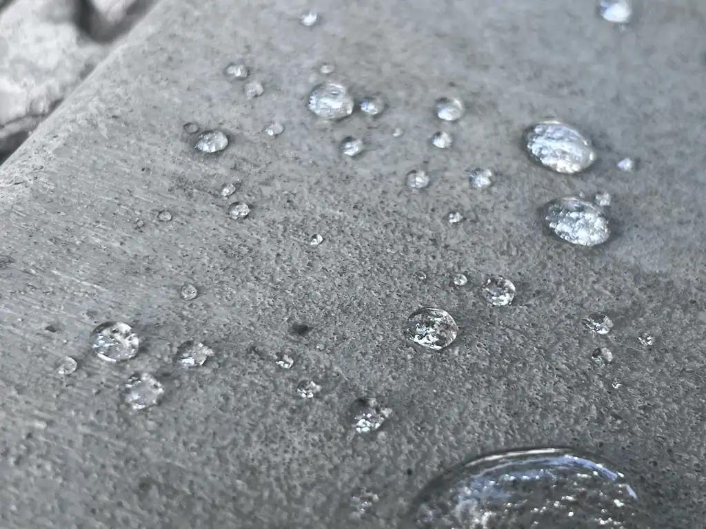 Close view of water beads sitting on a protected concrete surface