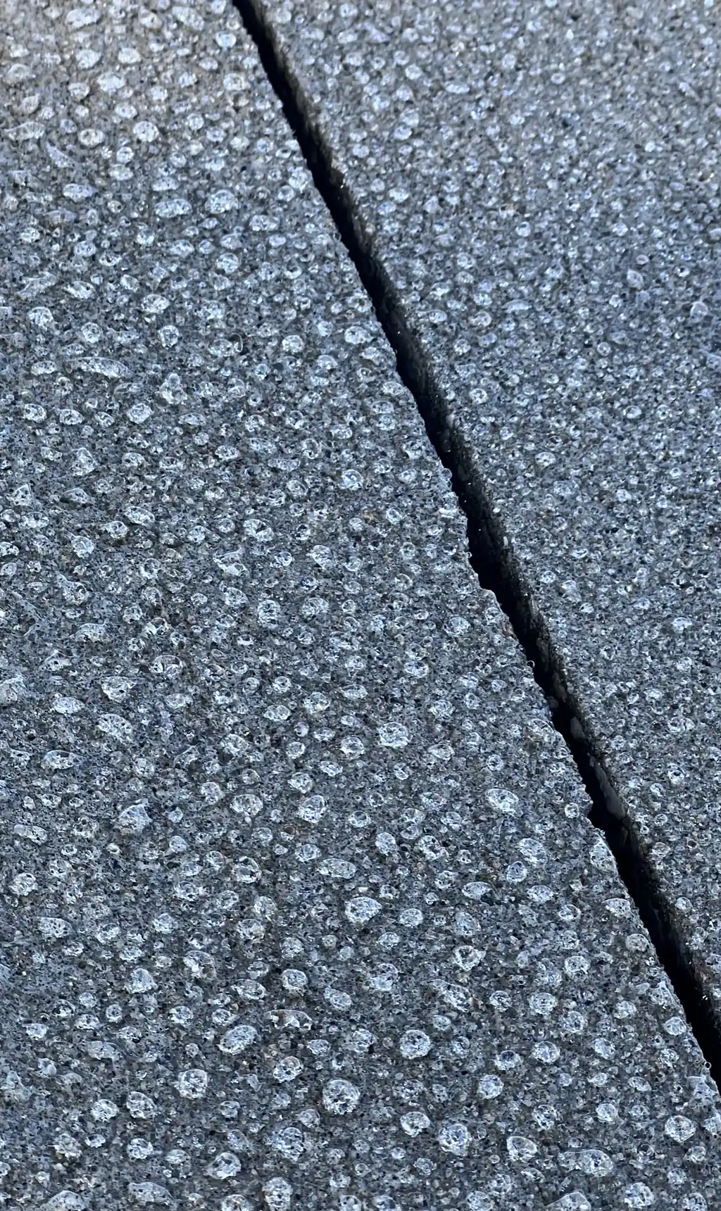 Water beads covering a protected concrete slab beside a control joint