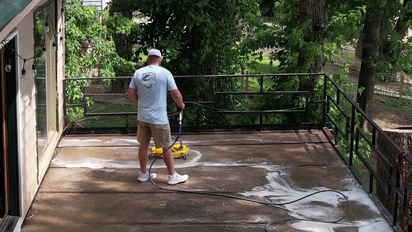 Crew member running a surface cleaner on a riverfront patio above the Ohio River