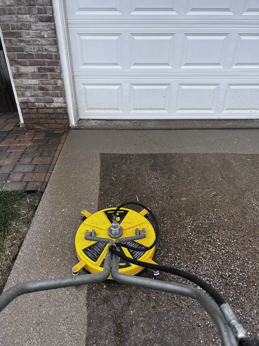 Yellow surface cleaner on a driveway next to a garage door